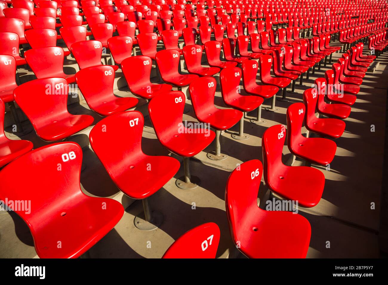 Red empty stadium chairs under the sun with nobody Stock Photo