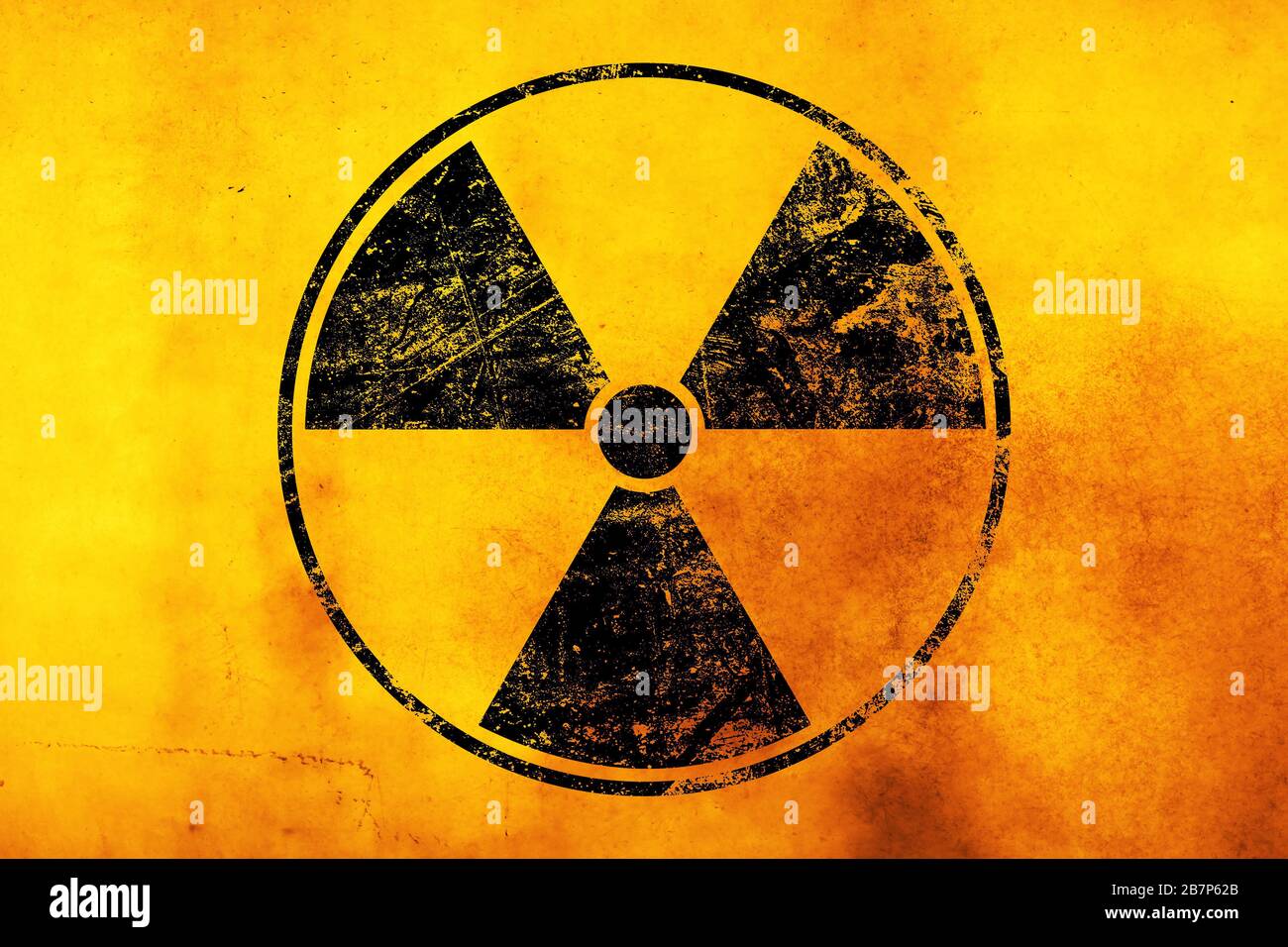 Black radioactive hazard warning sign painted over grunge yellow background with copy space Stock Photo