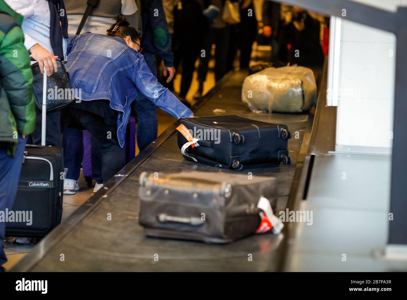 Otopeni, Romania - February 25, 2020: Woman lifts her luggage from the baggage carousel in Henri Coanda International Airport. Stock Photo