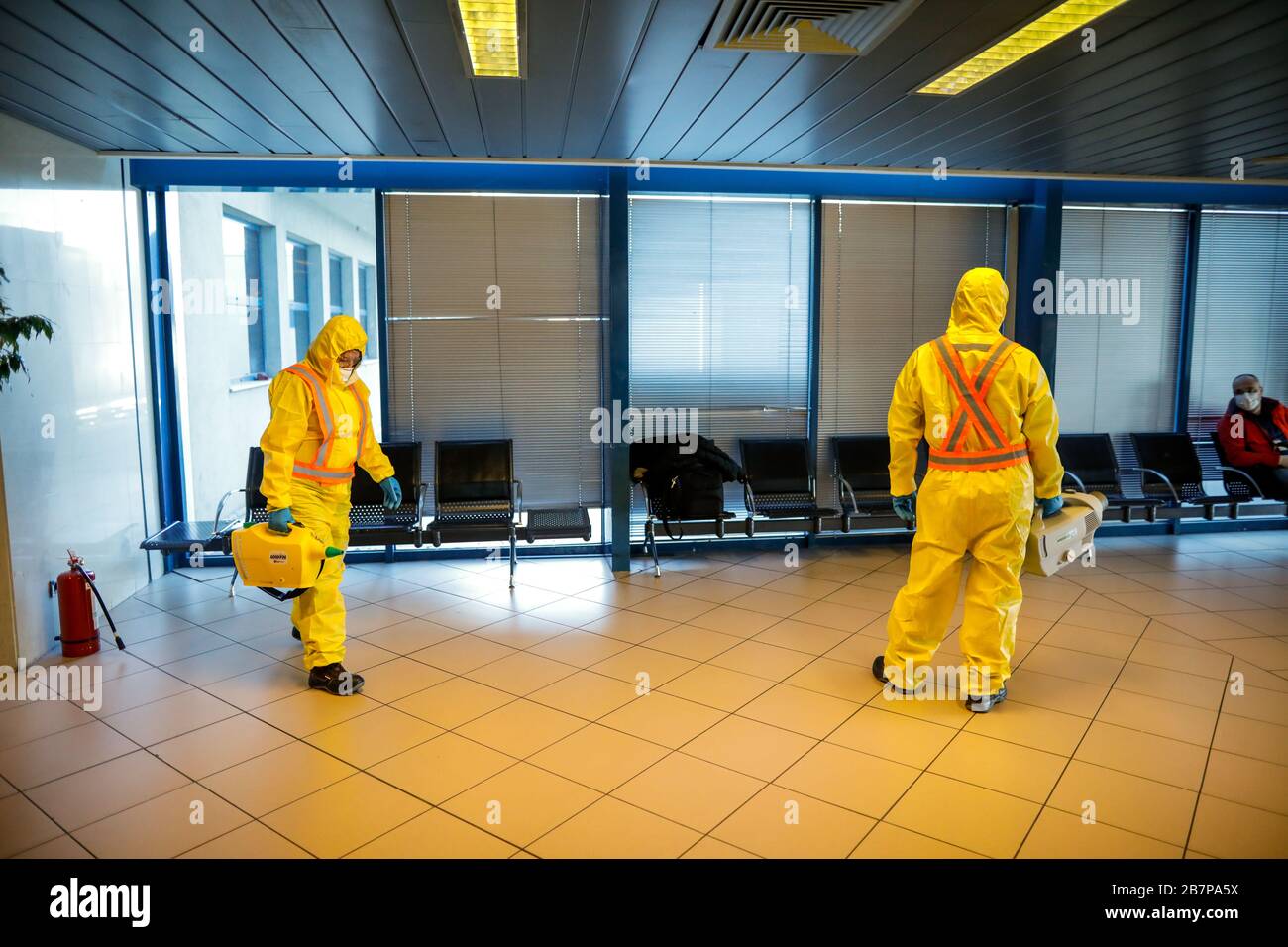 Otopeni, Romania - February 25, 2020: People wearing protective suits spray disinfectant chemicals on the Henri Coanda International Airport to preven Stock Photo