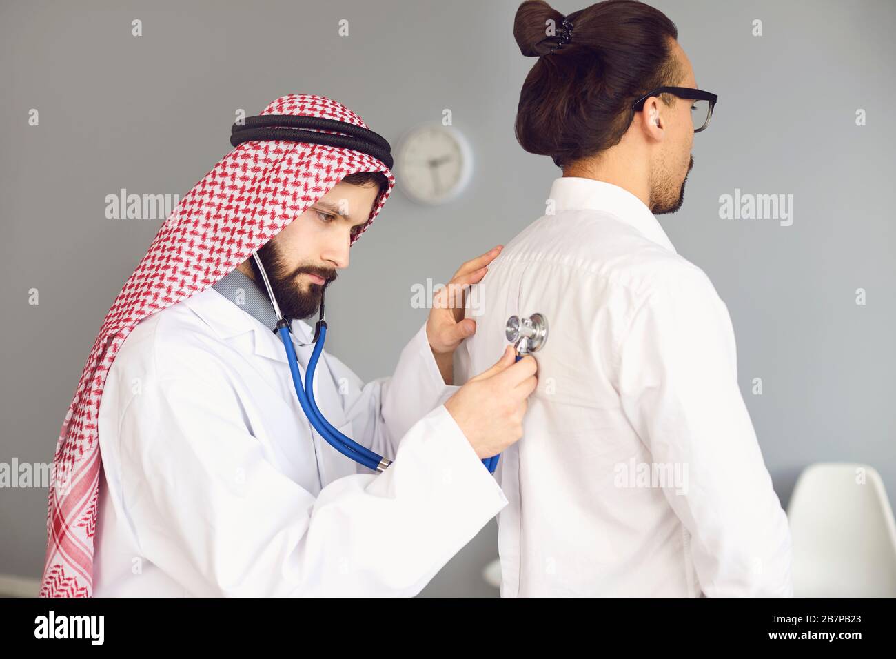 Arab doctor male listens in a stethoscope to a patient in a clinic