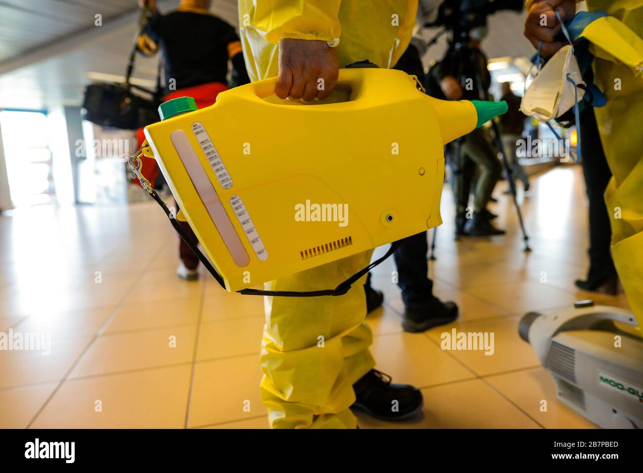People wearing protective suits spray disinfectant chemicals on an international airport  to prevent the spreading of the coronavirus. Stock Photo