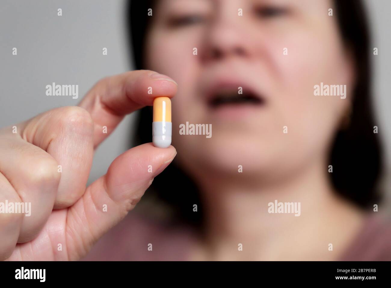 Woman takes a pill, girl putting capsule in open mouth. Sick female taking medicines, concept of antibiotic, vitamin, coronavirus prevention Stock Photo