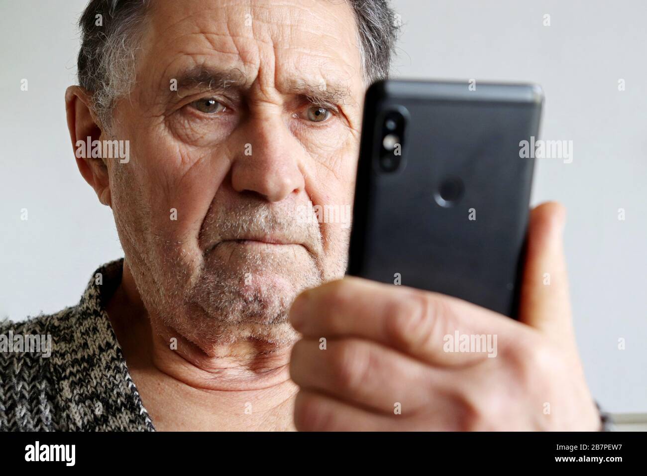 Elderly man using smartphone, mobile phone in male hands close up. Concept of online communication in retirement, sms, social media, bad news Stock Photo