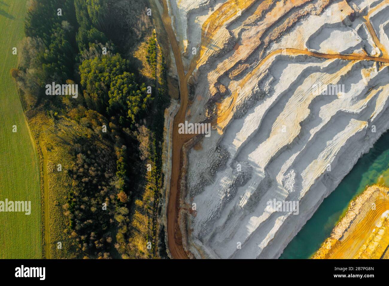 Top view on a sand quarry along a road. Sandpit is near a forest. Mining of natural resources or ore. Stock Photo