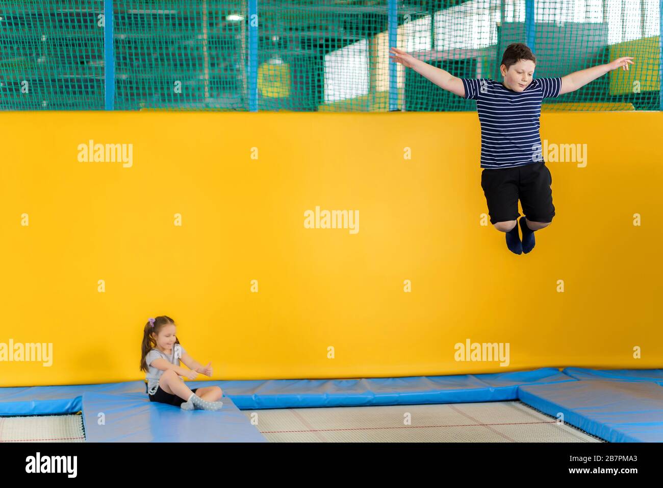 Happy smiling small kids jumping on indoors trampoline in entertainment ...