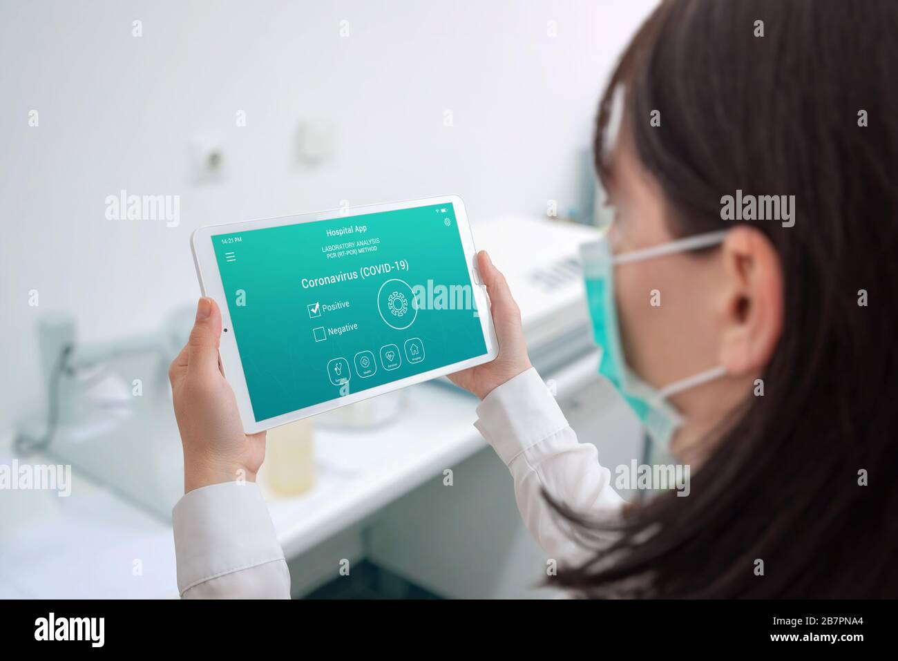 Woman holding tablet with coronavirus positive test concept. Hosital laboratory interior. Scientist with mask Stock Photo