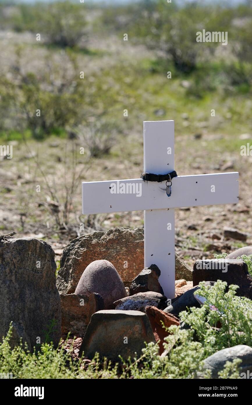 A white cross stands in the Arizona desert marking the burial site for a pet. Stock Photo