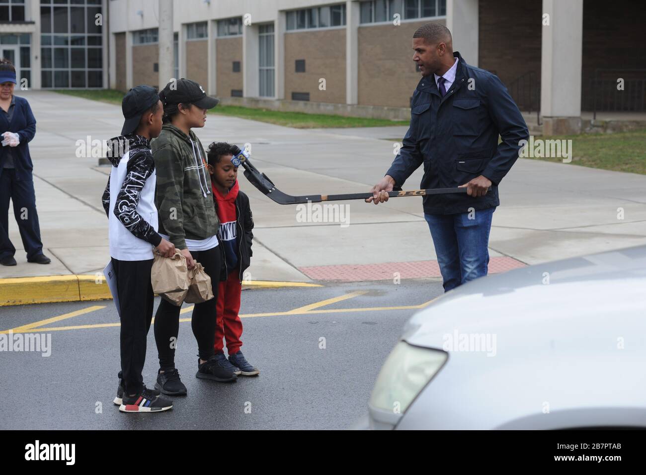 Bensalem, Pa., USA. 17th Mar 2020. From left, Sebastian Kitchens, Maryjoy  Esguerra and Breven Kitchens who picked up lunches from the school while  school is closed, speak with reporter Howard Moore, who