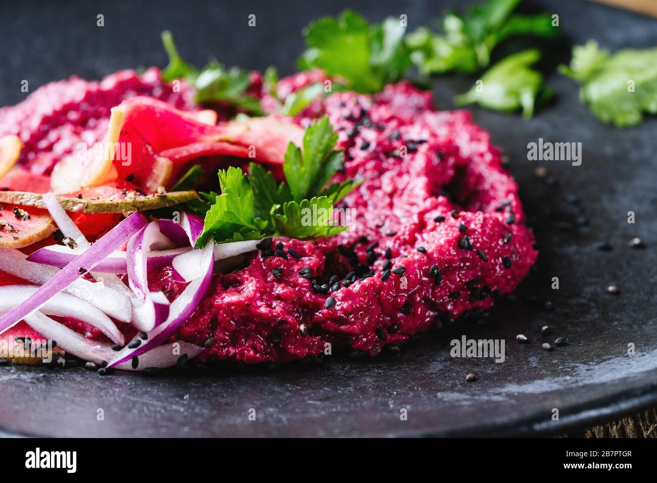 Beetroot horseradish  hummus with pickled watermelon radishes on rustic wooden table, plant based food, close up Stock Photo