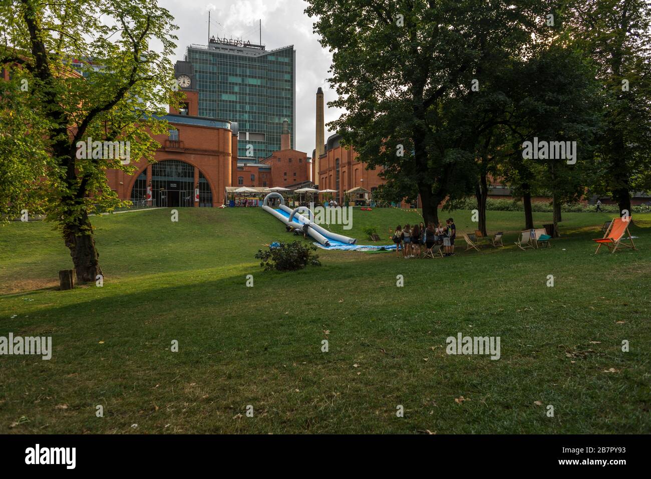 People relax in Park Dabrowskiego in Poznan.  In the background Shopping, Arts and Business Center 'Stary Browar'. Stock Photo