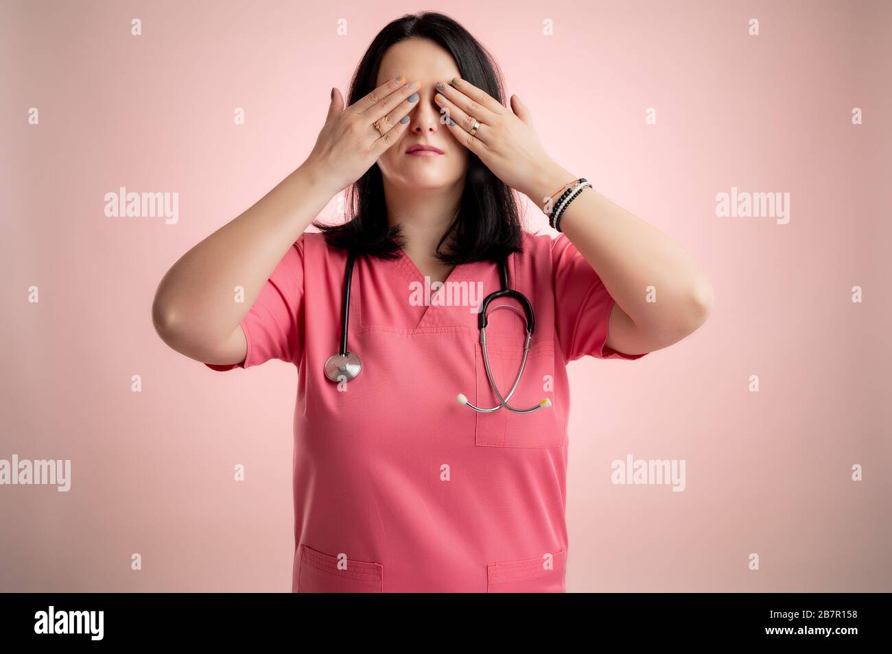 Portrait of beautiful woman doctor with stethoscope wearing pink scrubs