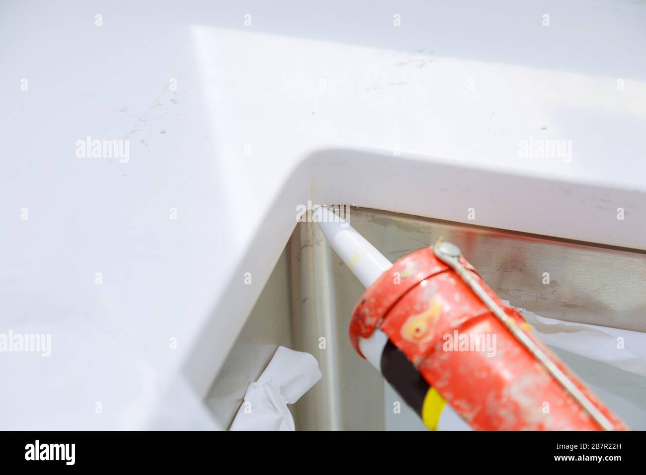Worker installing granite sink in kitchen silicone sealant on granite