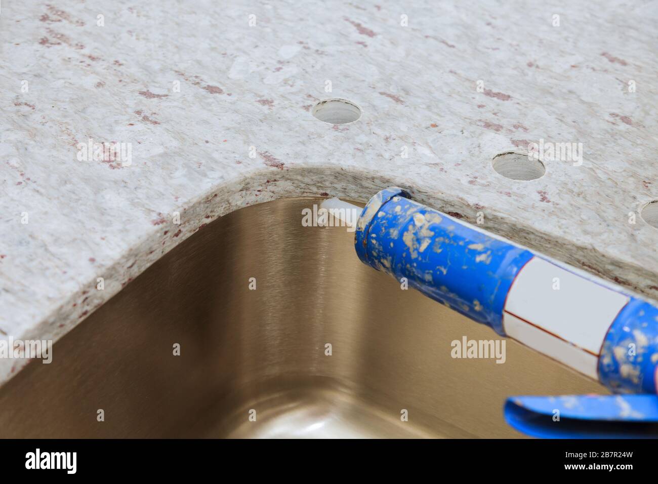 Gun putting silicone sealant to installing a kitchen sink with modern