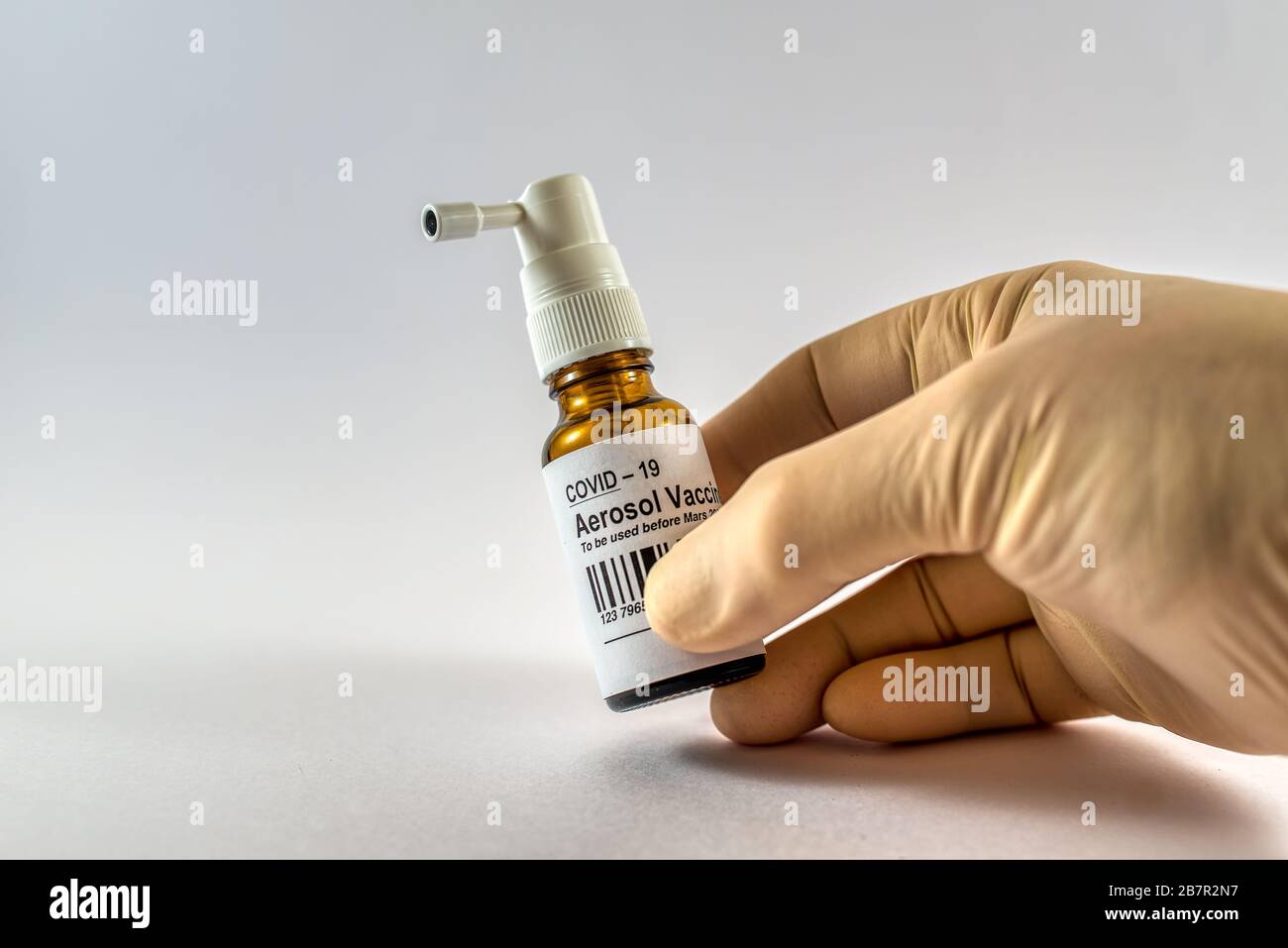 Hand with latex glove holding a bottle of corona aerosol vaccine against white background, Denmark, Mars 17, 2020 Stock Photo