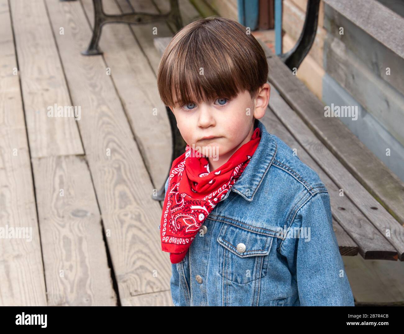 Adorable, blue eyed little boy with a cute pout, dressed in a western style  outfit with a red bandana and blue jeans Stock Photo - Alamy