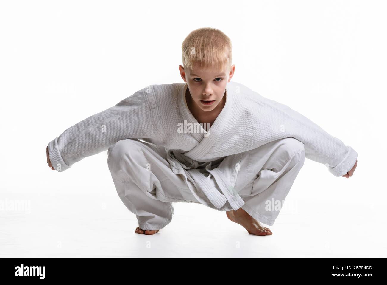 Martial arts student dressed in a kimono performs a squat Stock Photo