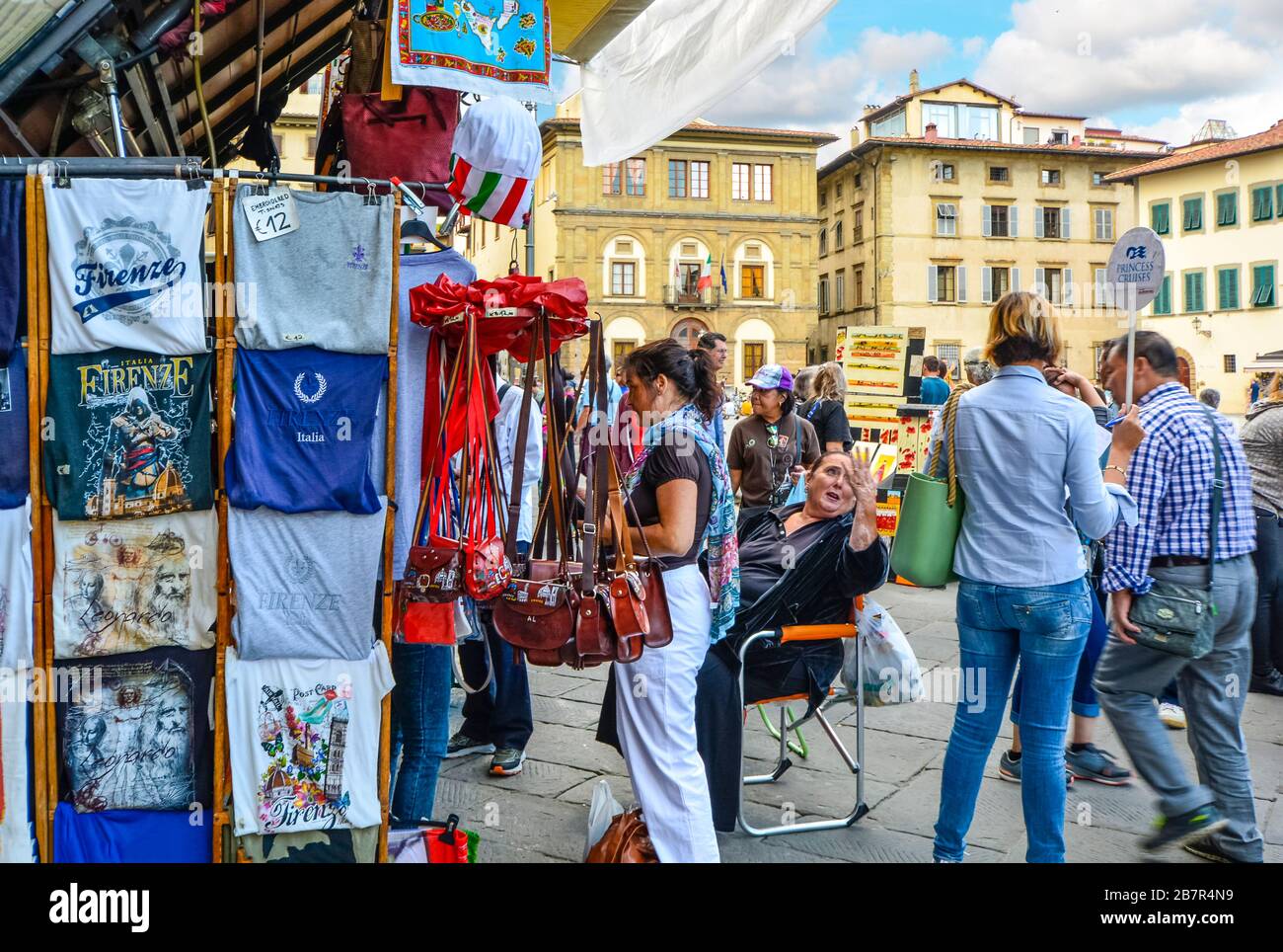 Tourists and tour guides shop for souvenirs and talk with local vendors and merchants at an outdoor market on Piazza Santa Croce in Florence, Italy. Stock Photo