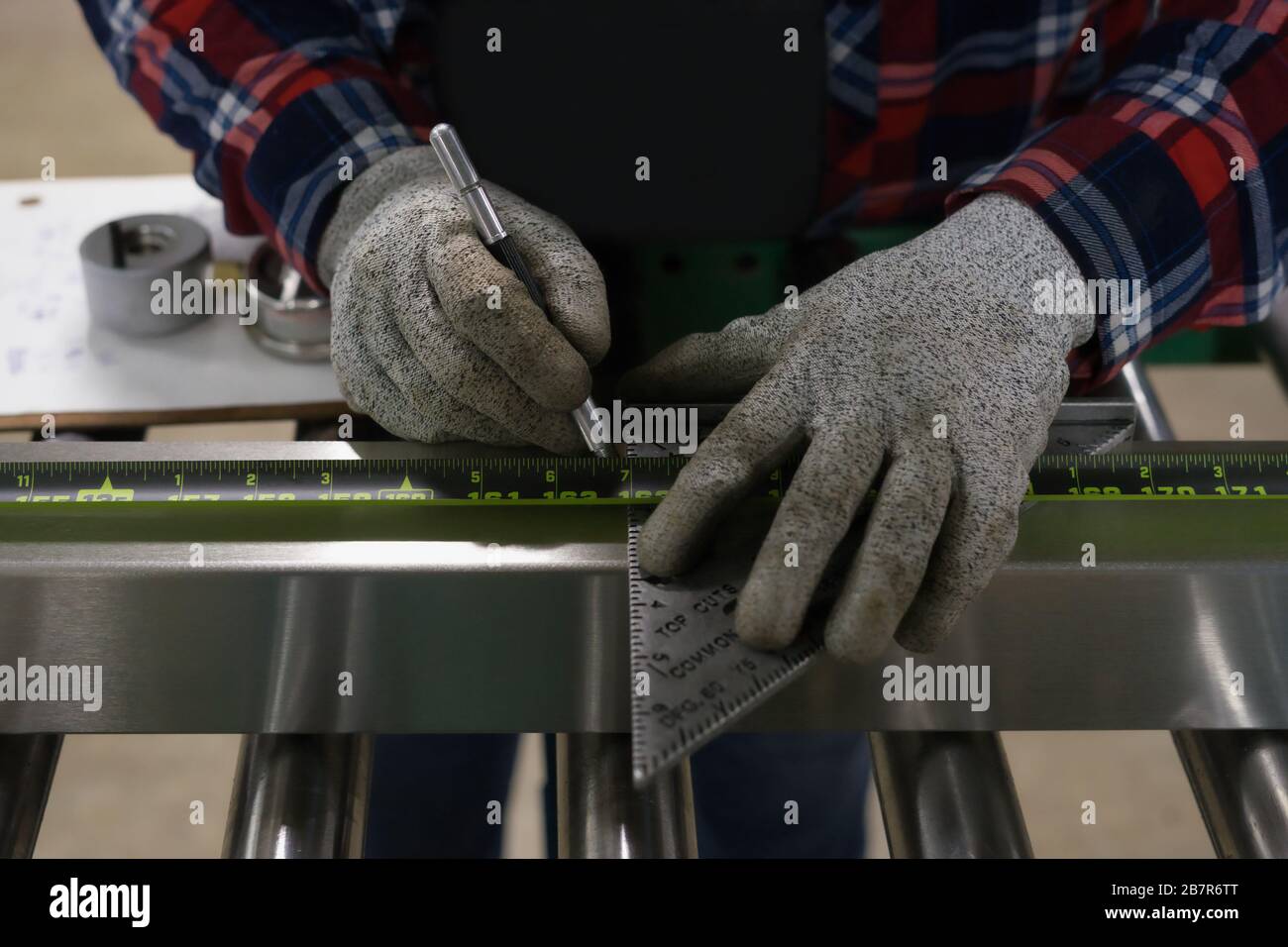 A worker measures some steel to be used to make equipment that extracts oil from hemp. Stock Photo