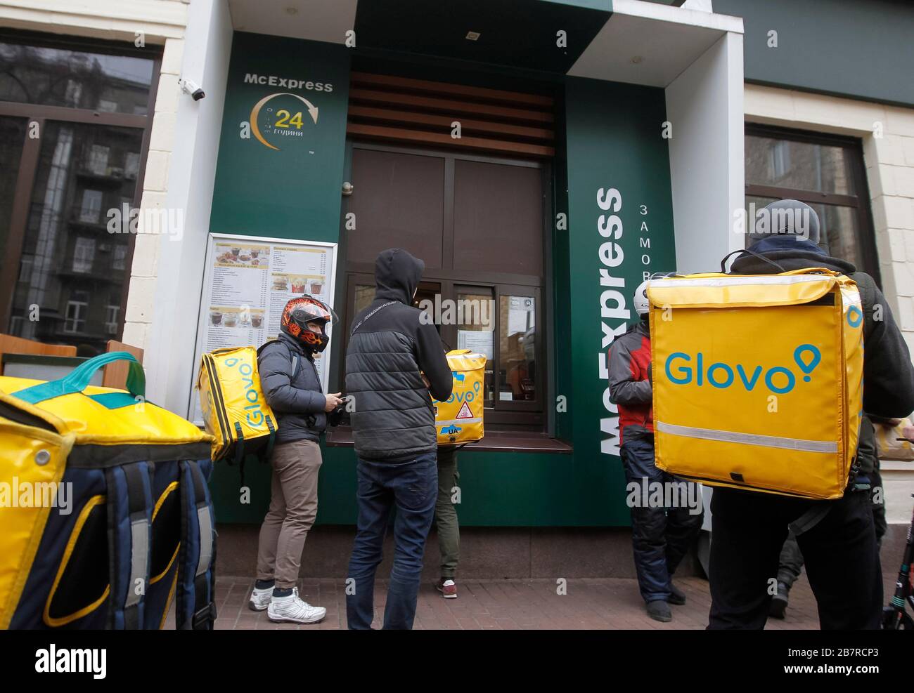 Glovo delivery men take food outside McDonald's fast food point in Kiev.The Ukrainian Government at its extraordinary meeting decided to suspend all air, rail and bus services between cities and regions of Ukraine from March 18 and closure the subway in cities from March 17, 2020, as quarantine measures against the spread the COVID-19 coronavirus in Ukraine. Starting March 17, catering establishments' restaurants, cafes, shopping and entertainment centers, other entertainment establishments, fitness centers, cultural establishments must temporarily suspend their work. Stock Photo