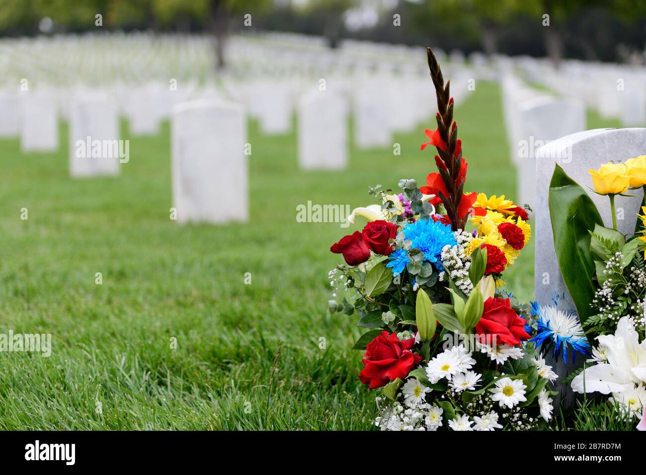 A floral arrangement at a cemetery with gravestones on a national holiday. Memorial Day Stock Photo