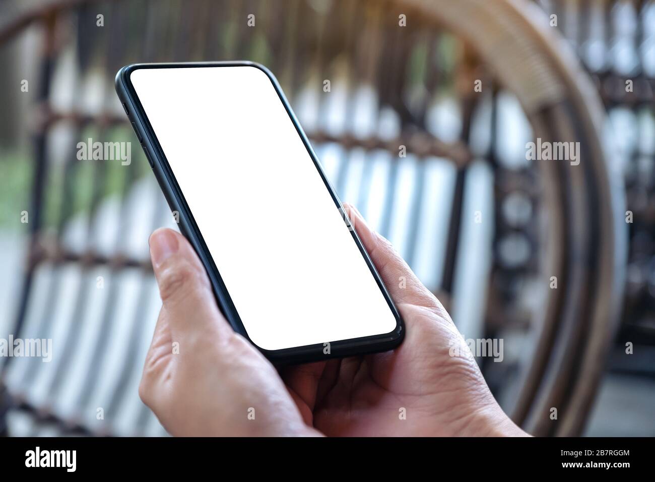 Mockup image of hand holding black mobile phone with blank white screen ...
