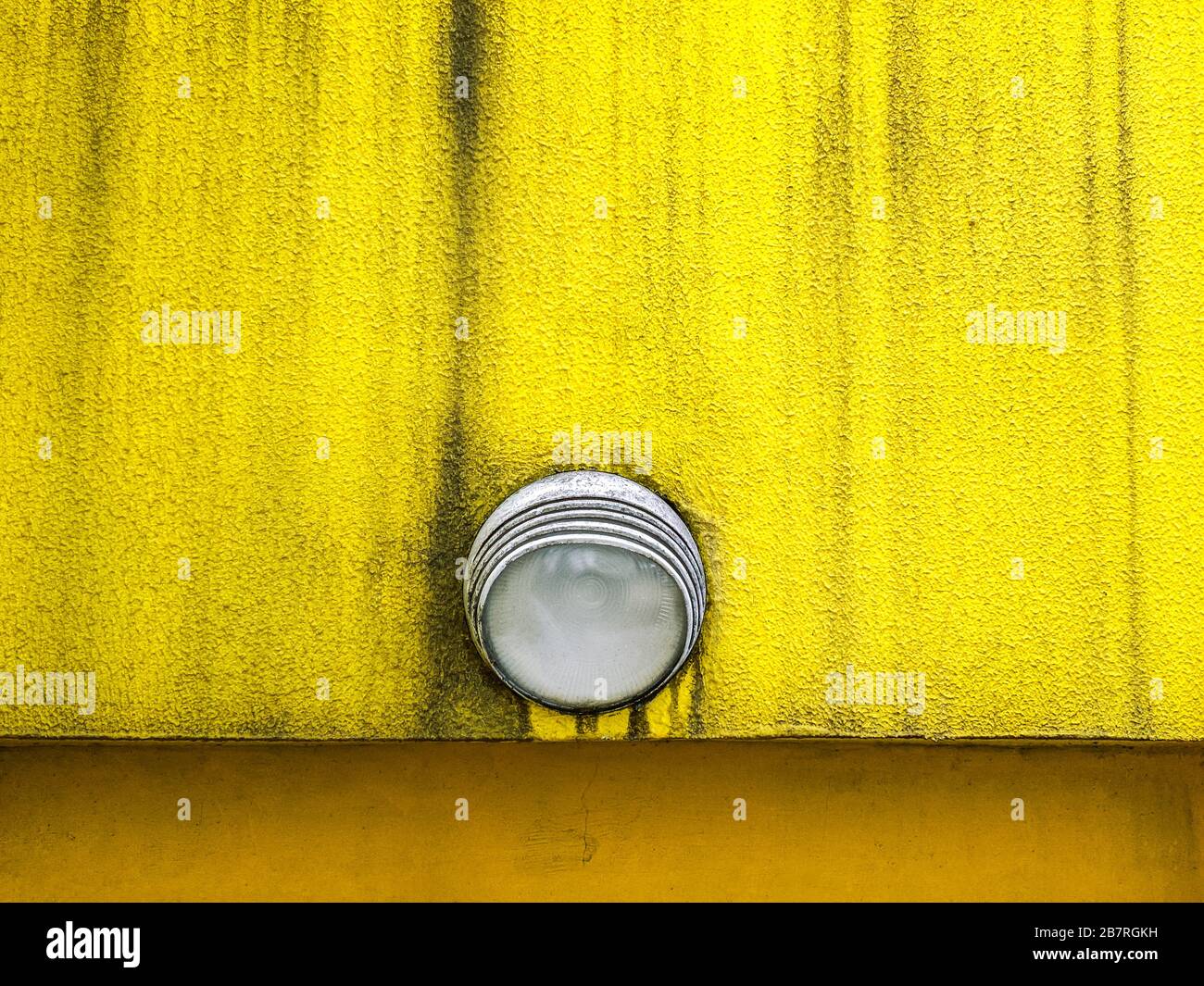 lighting fixture on weathered textured plaster wall painted yellow