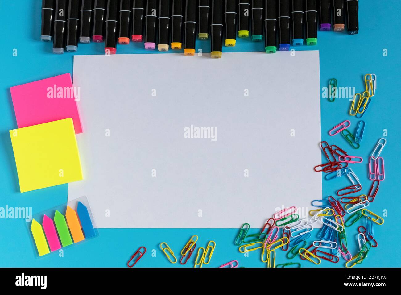 Multi-colored markers, paper clips, stickers and paper on a blue background. Drawing and creativity. Stock Photo