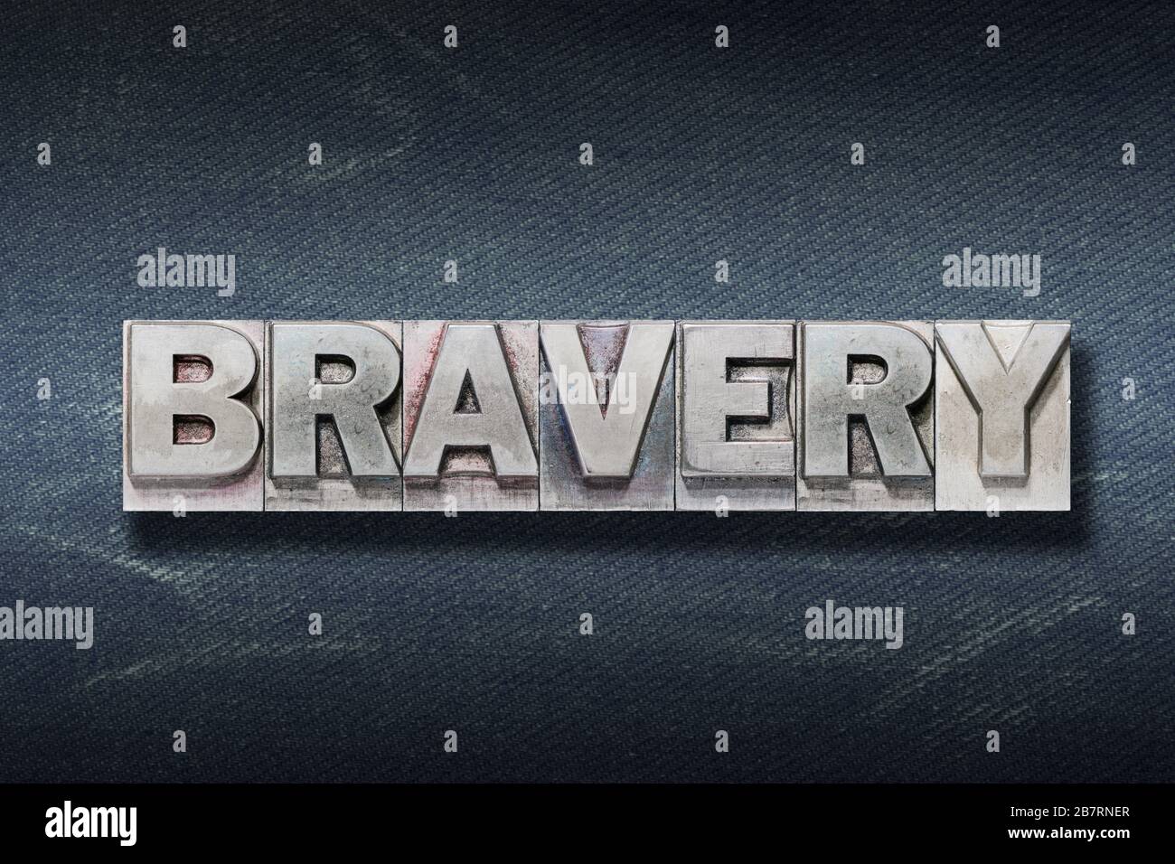 bravery word made from metallic letterpress on dark jeans background Stock Photo