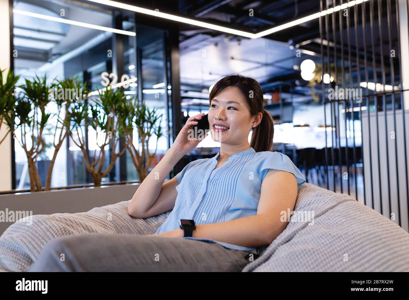 Asian woman having a phone call in a bean bag Stock Photo