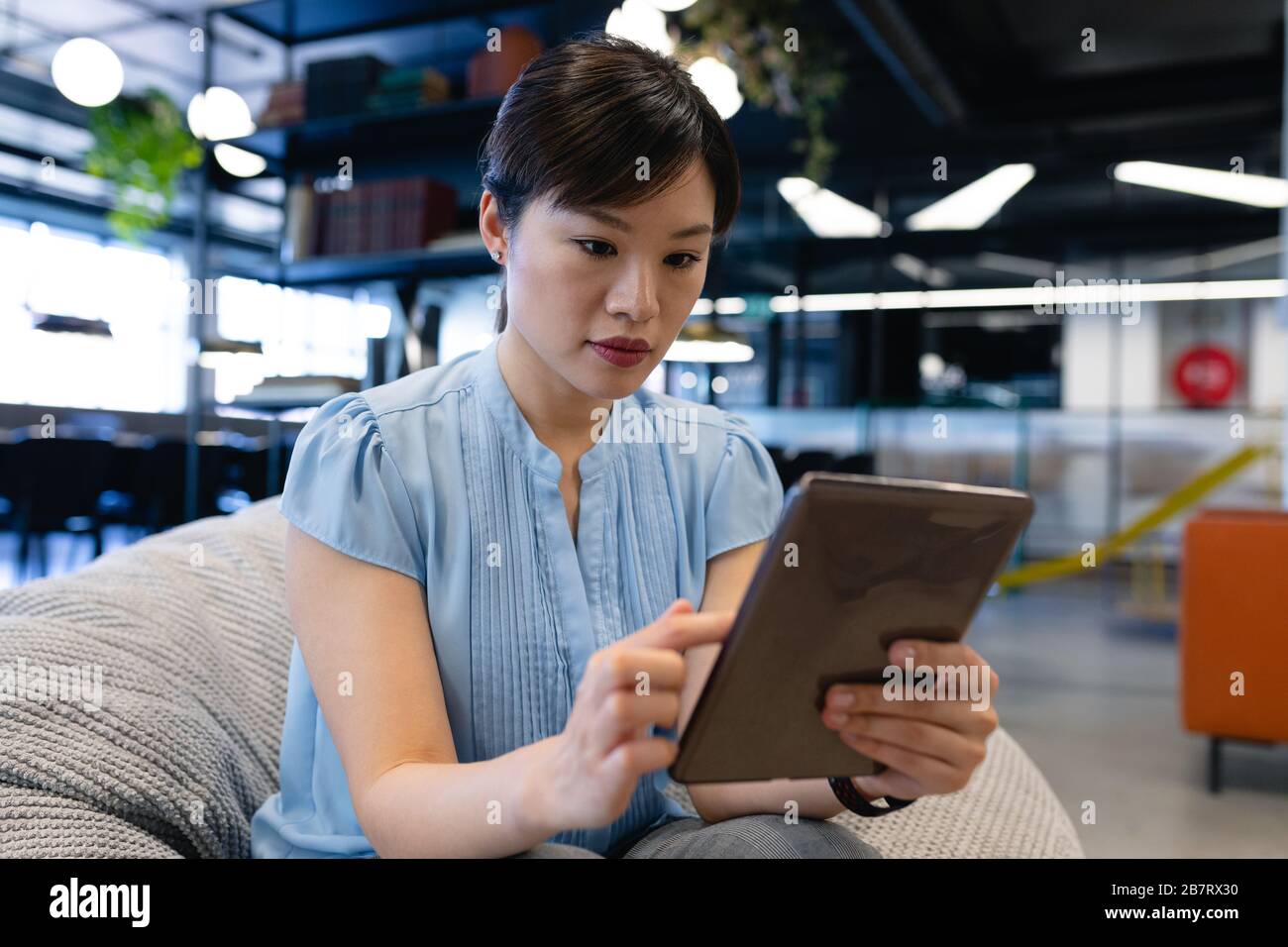 Asian woman sitting in a bean bag and holding a digital tablet Stock ...