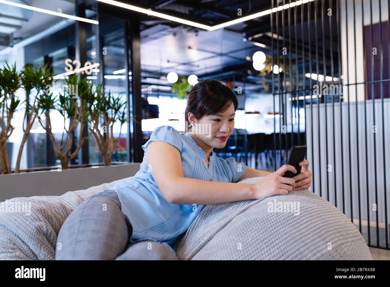 Asian woman using her phone in a bean bag Stock Photo - Alamy