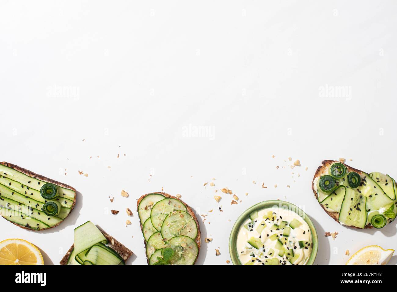 top view of fresh cucumber toasts with seeds, mint and basil leaves and