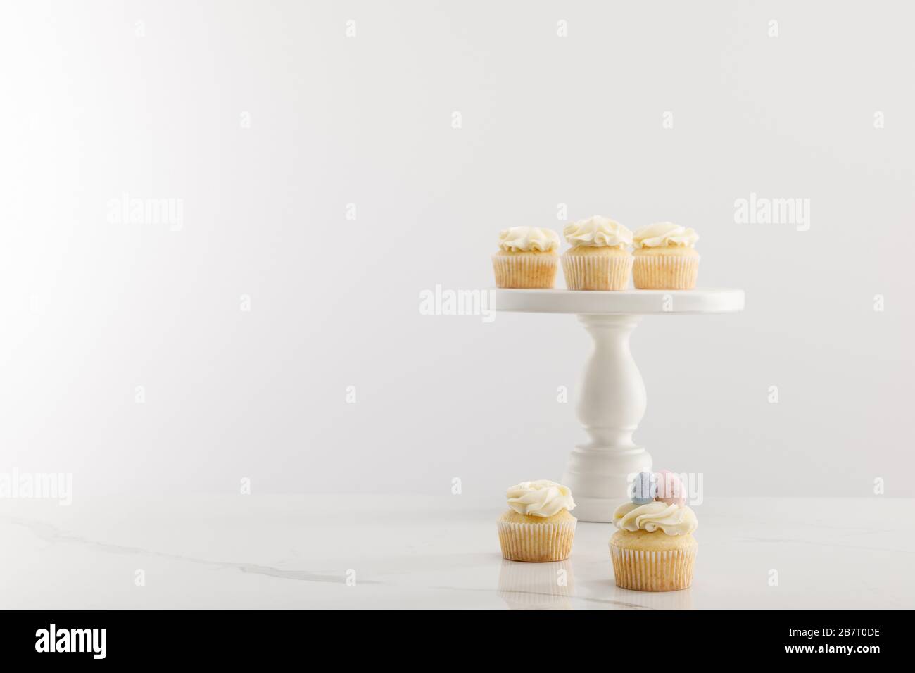 Tasty easter cupcakes on cake stand isolated on grey Stock Photo