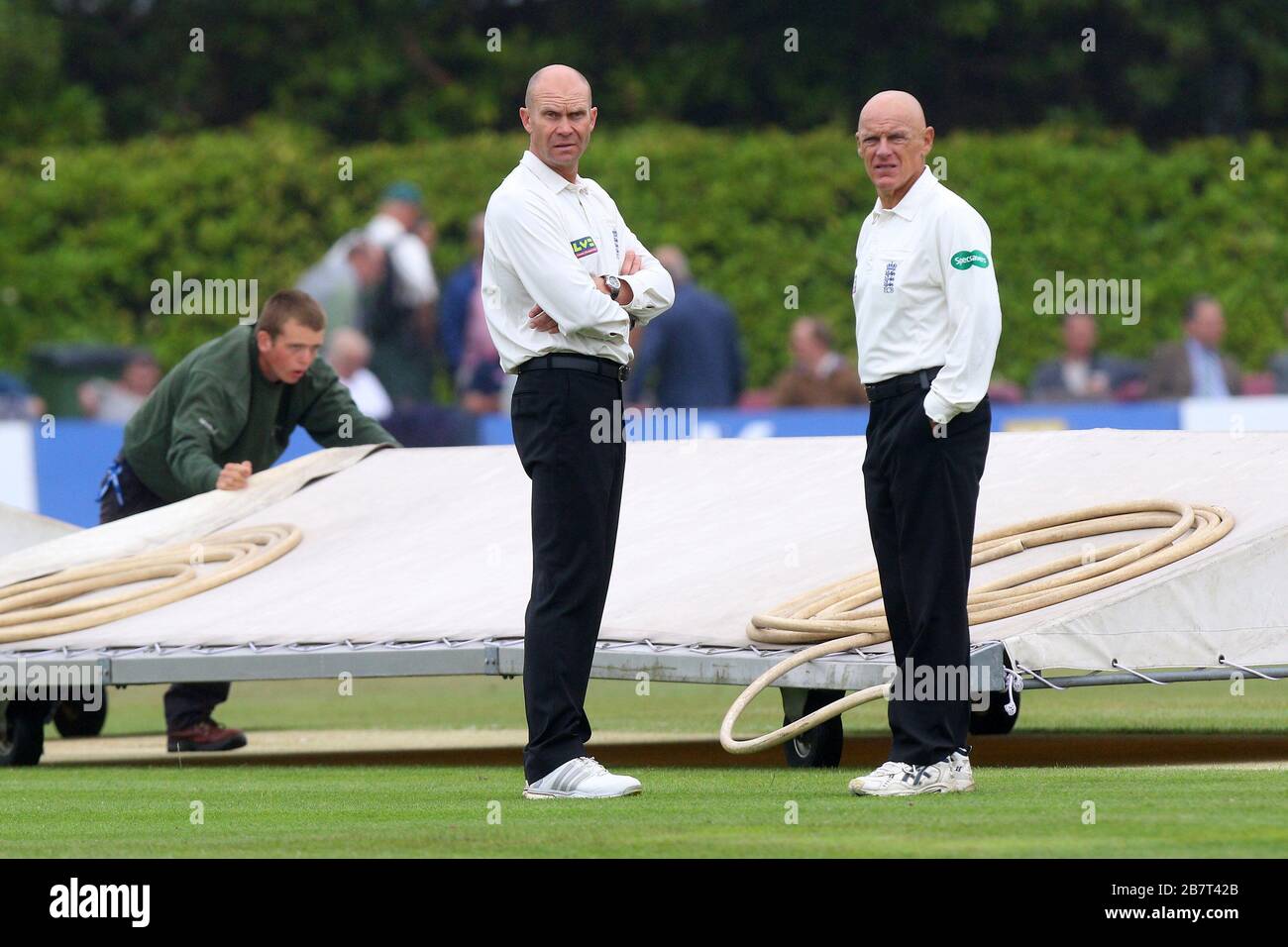 Umpires Jeffrey Evans (R) and Mike Burns look on as the covers are moved into position as rain falls on Day Two Stock Photo