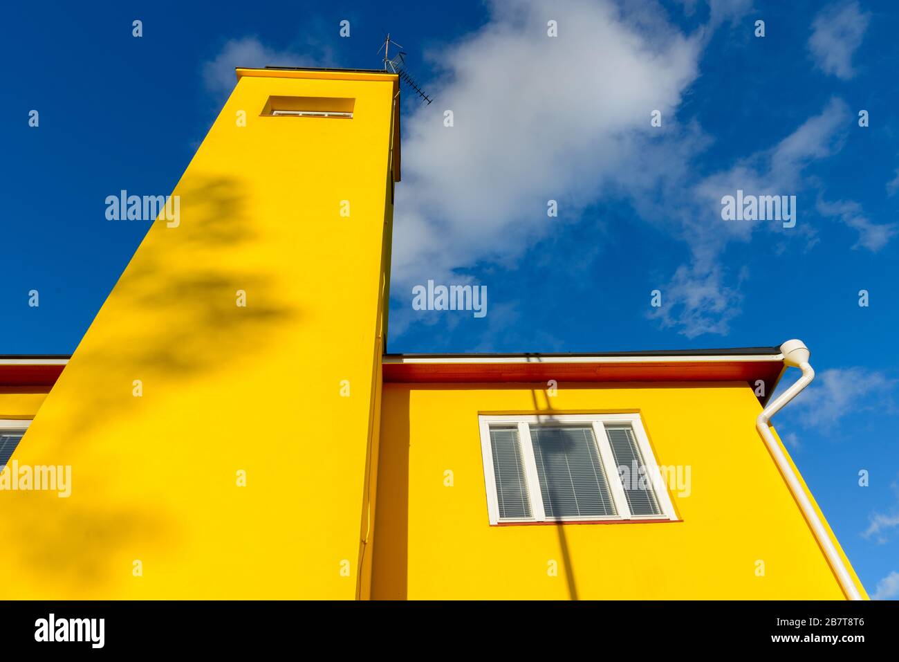 Yellow building with white windows against view of blue sky Stock Photo