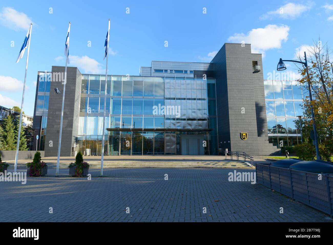 Entrance of modern building of Naantali city with three Finnish flag poles in front Stock Photo