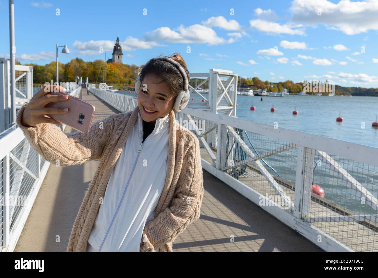 Young happy Asian woman smiling while taking selfie picture with mobile ...