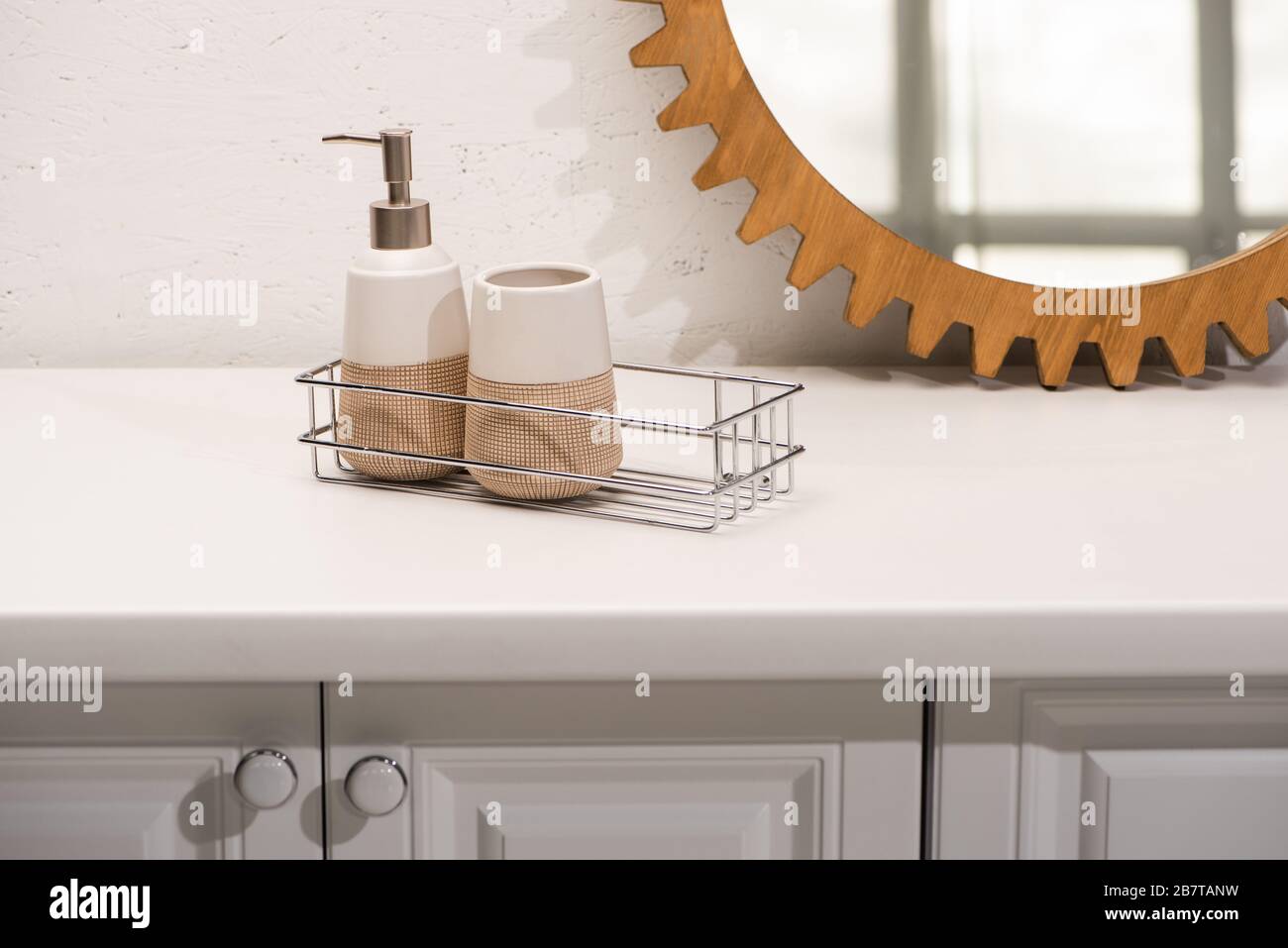Dispenser liquid soap, toothbrush holder on shelf near round mirror on ...