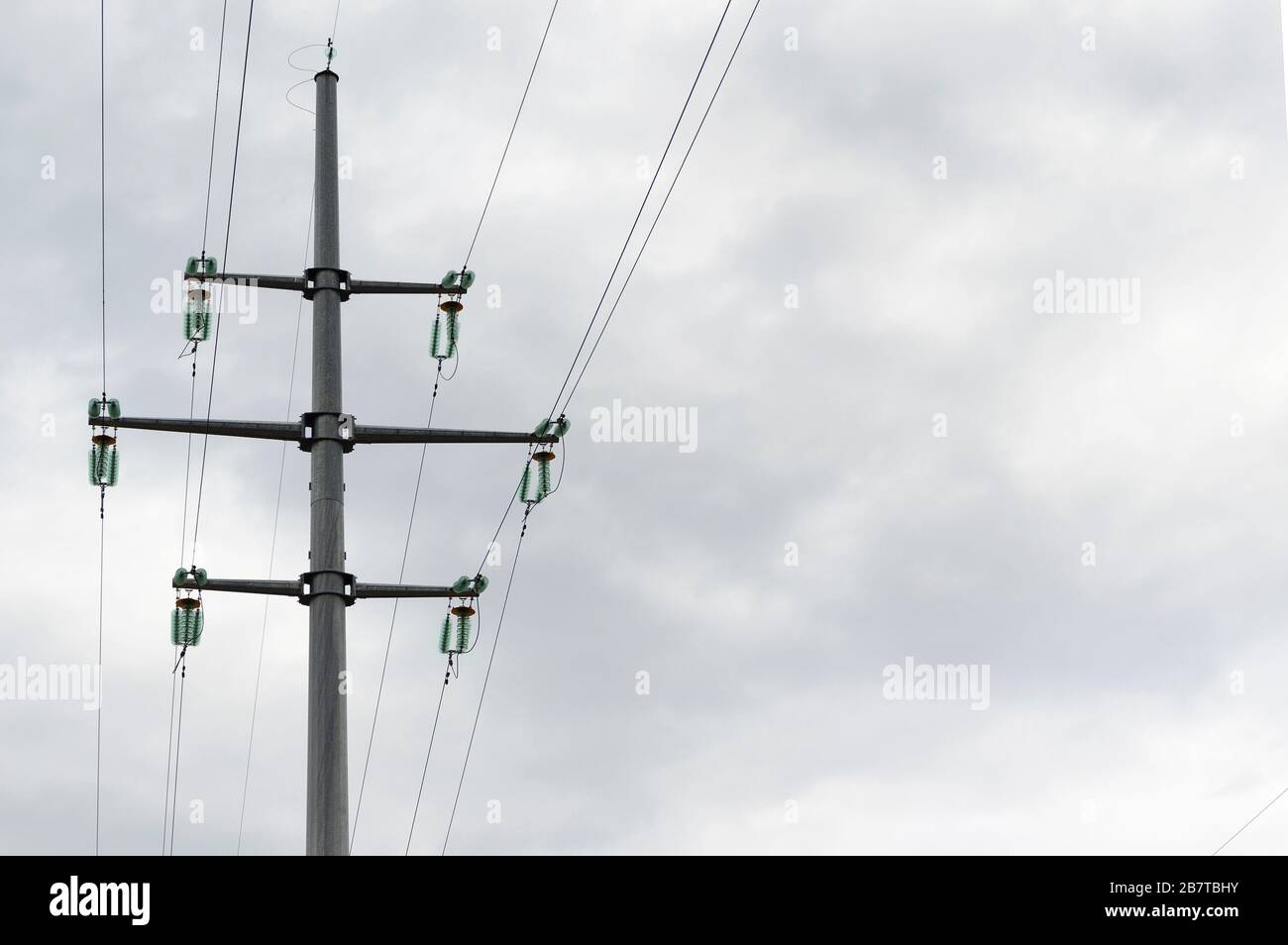 Pillar and power lines against a cloudy sky Stock Photo - Alamy