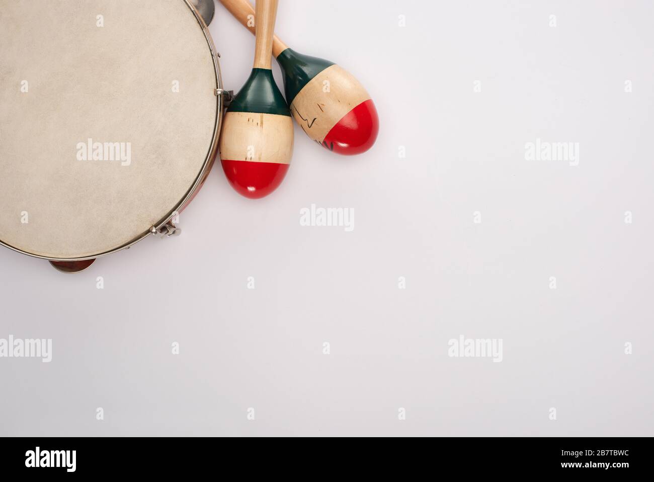 Top view of wooden maracas near tambourine on white background Stock