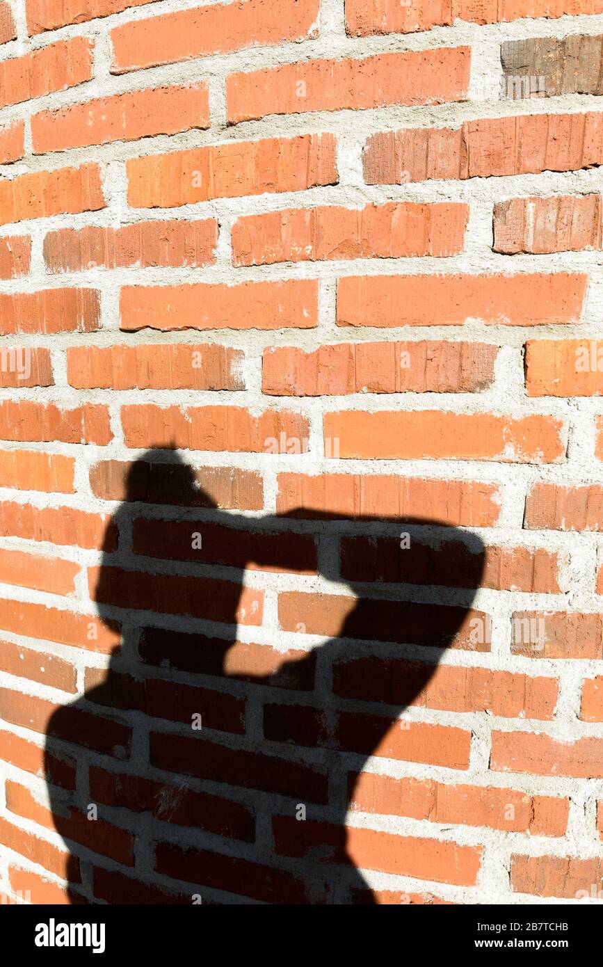 Shadow of man photographer taking picture against brick wall Stock Photo