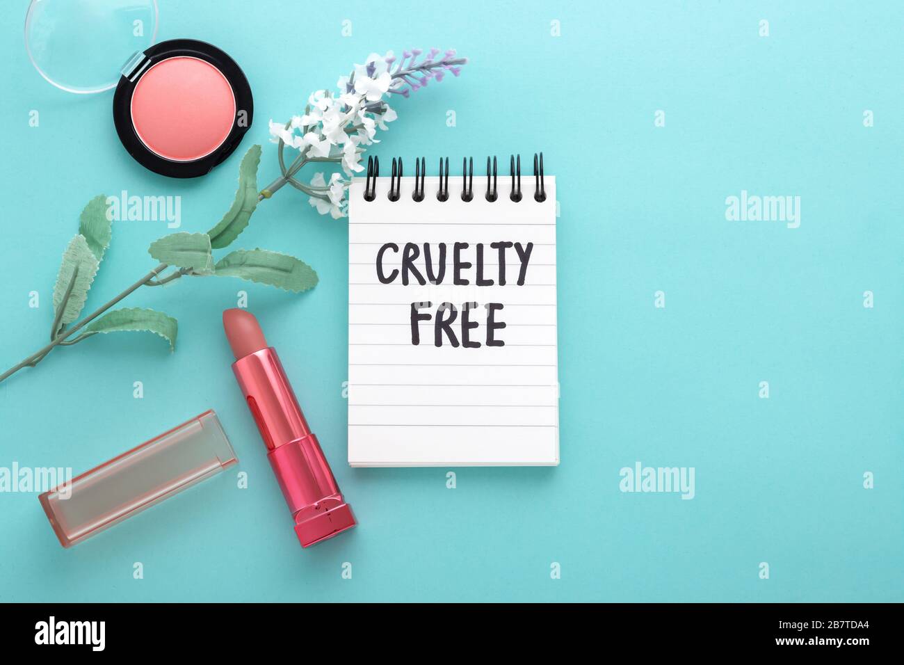 Cruelty free concept with lipstick, blush, and flowers on blue background, with space flat lay Stock Photo