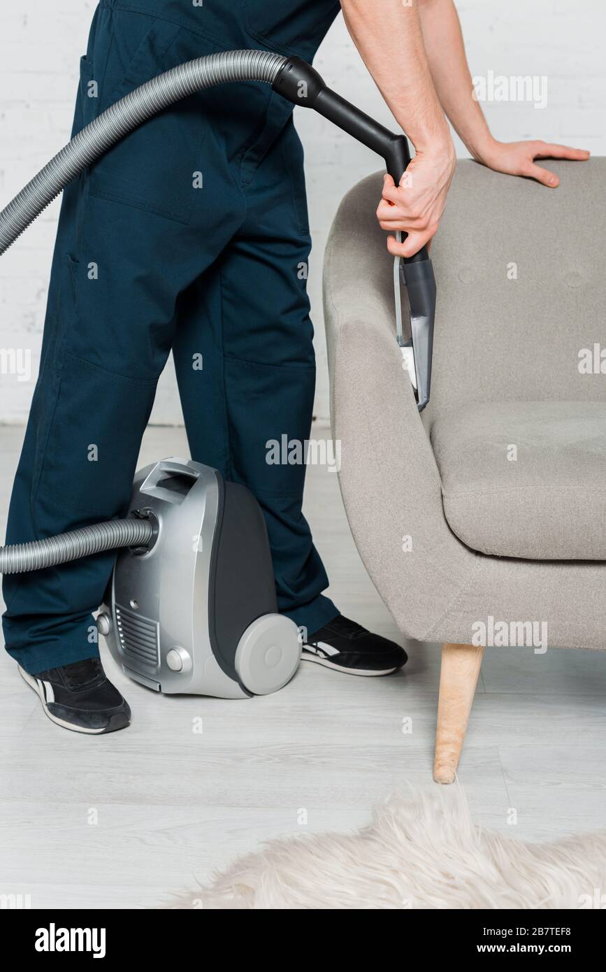 cropped view of young cleaner in uniform dry cleaning armchair with