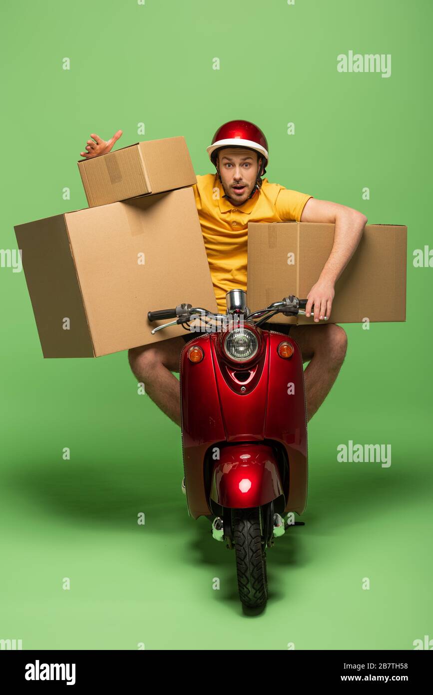 delivery man in yellow uniform on scooter with boxes on green Stock ...