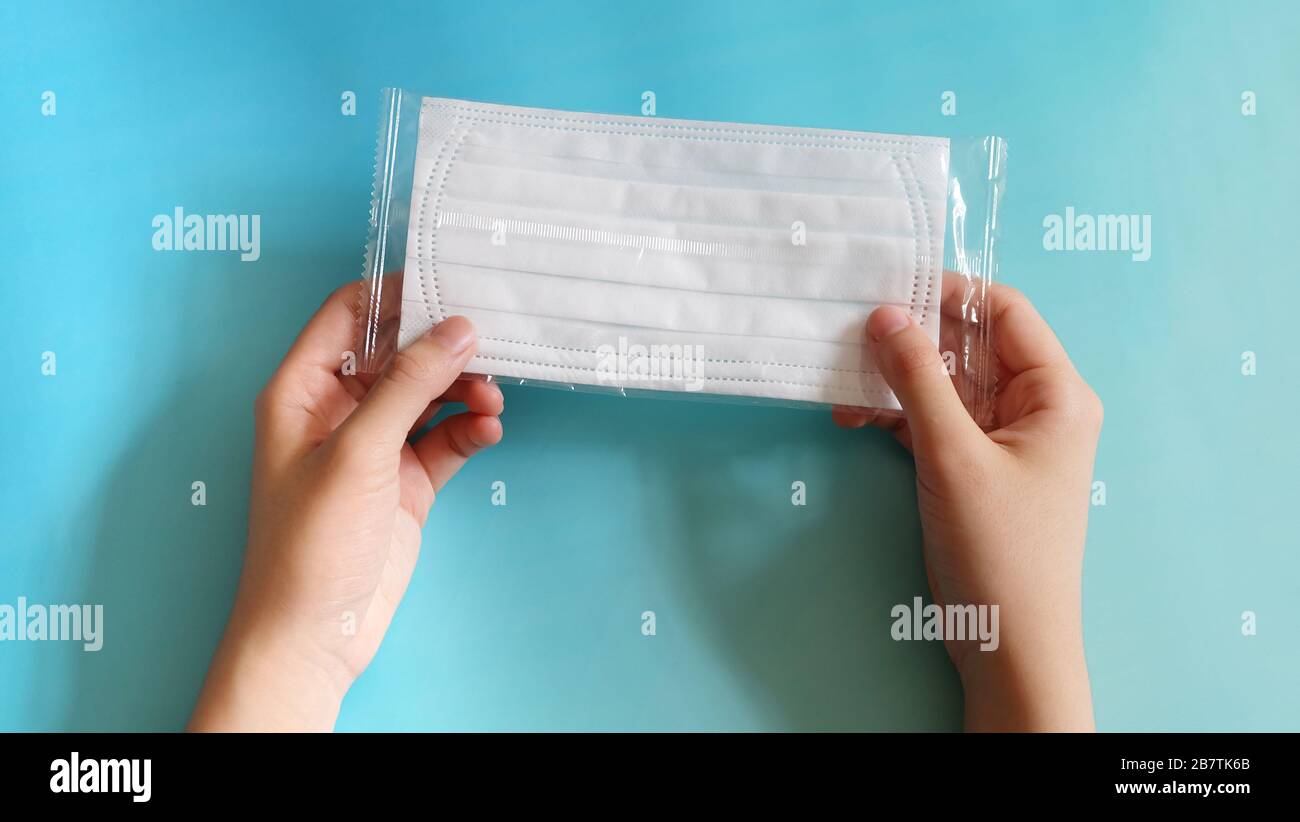 Hand holding a piece of face mask packed in an individual transparent packaging. Top view. Stock Photo