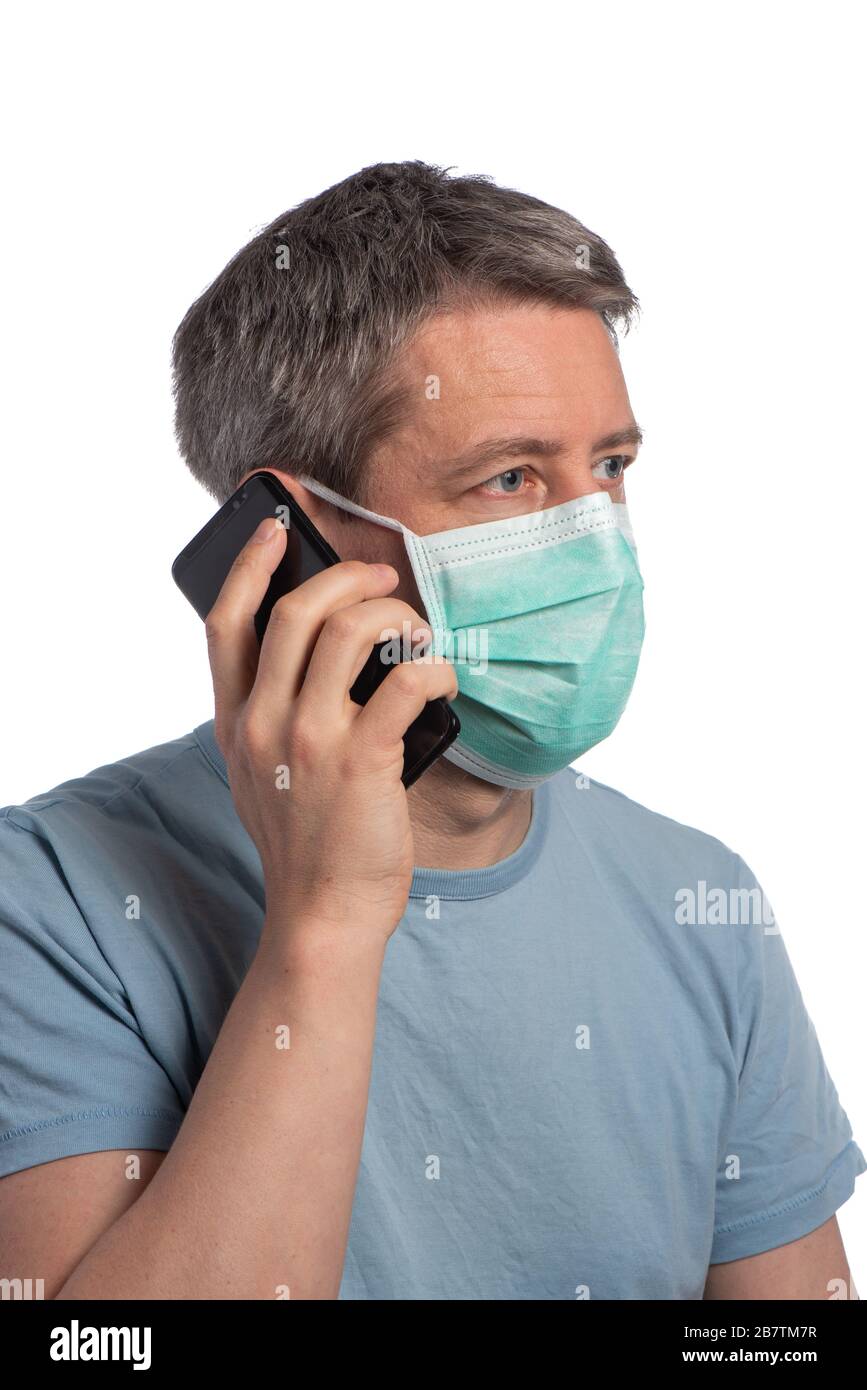 Caucasian man wearing a protection and making a phone call with a cell phone mask on a white background Stock Photo