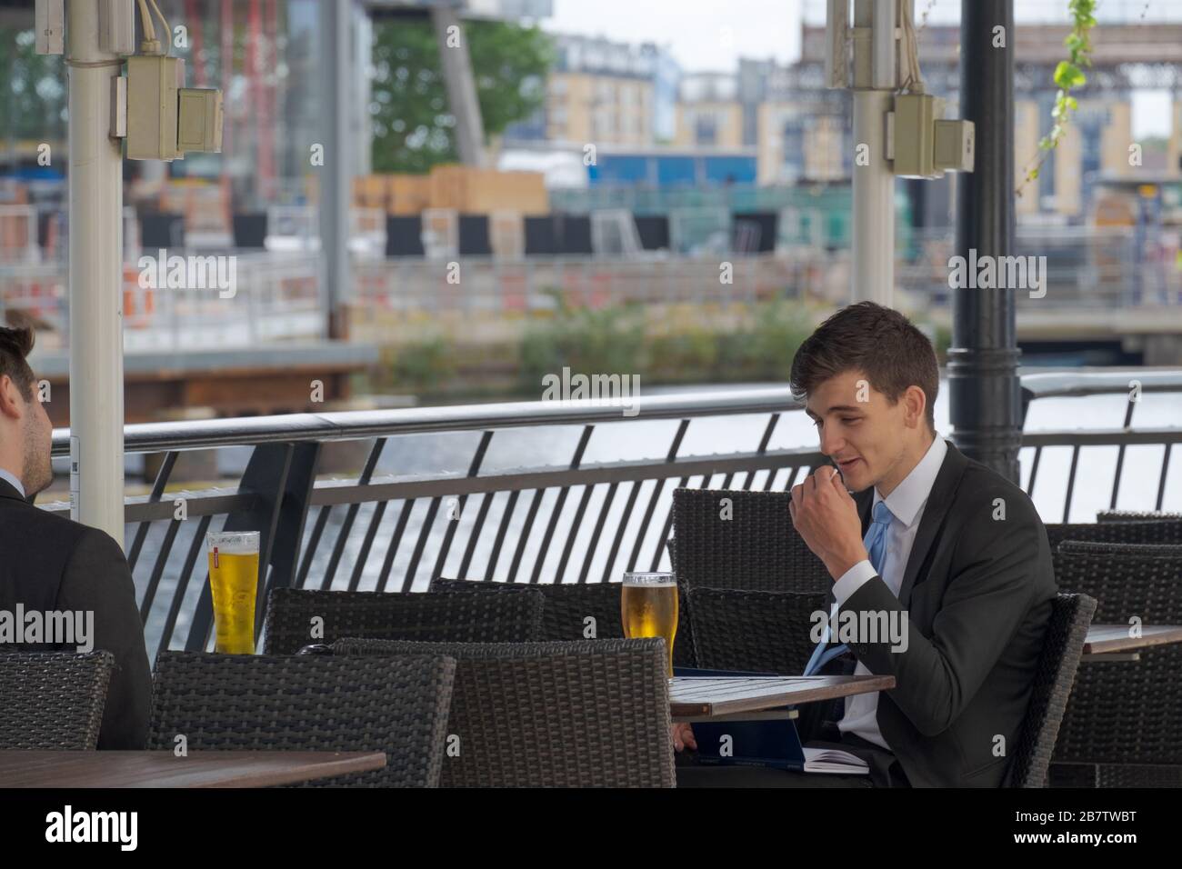 Two business men chat and drink beer at outside bar. Canary Wharf, London Docklands, UK. Stock Photo