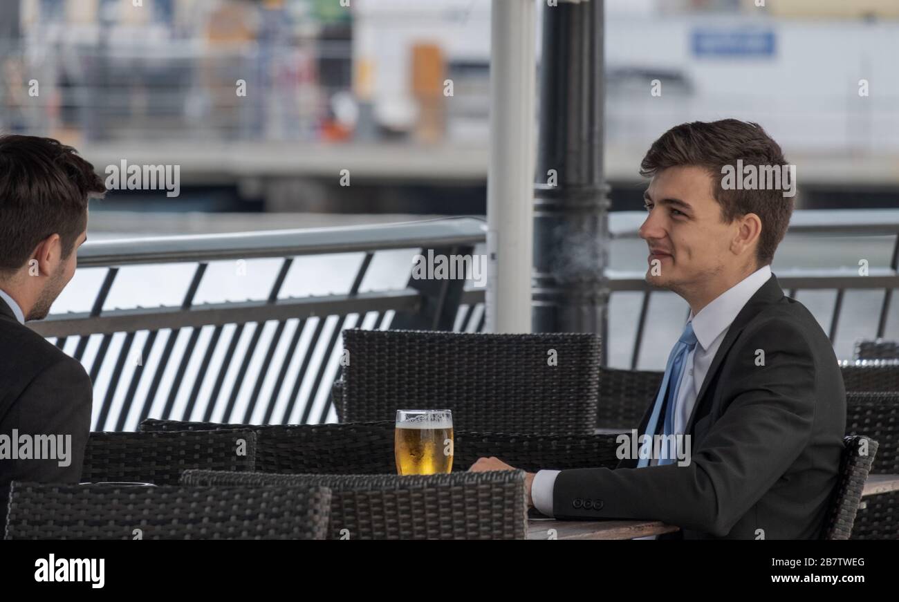 Two business men chat and drink beer at outside bar. Canary Wharf, London Docklands, UK. Stock Photo