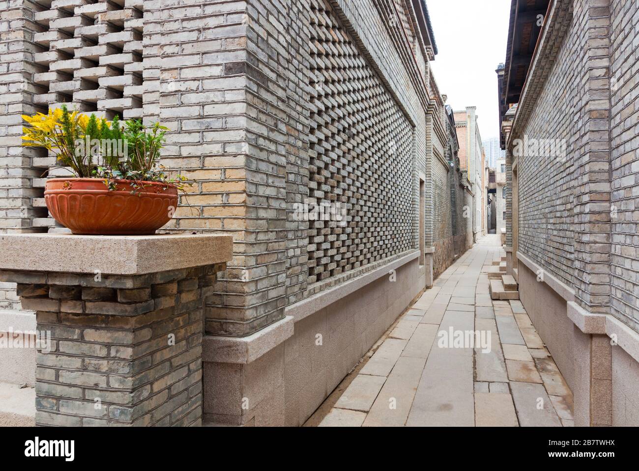 A characteristic alley of the retro style Chinese village, with brick houses and flagstone pavement, flower on pot decorated in entrance, Fuzhou,Fujia Stock Photo